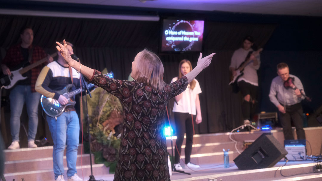 A person worshiping with their hands in the air at Kingsland Church