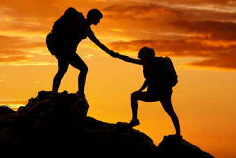 silhouette of friends helping while hiking