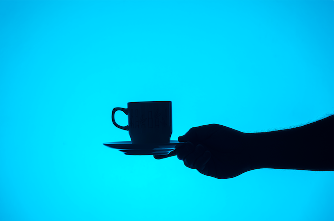 silhouette of a hand holding a cup of coffee